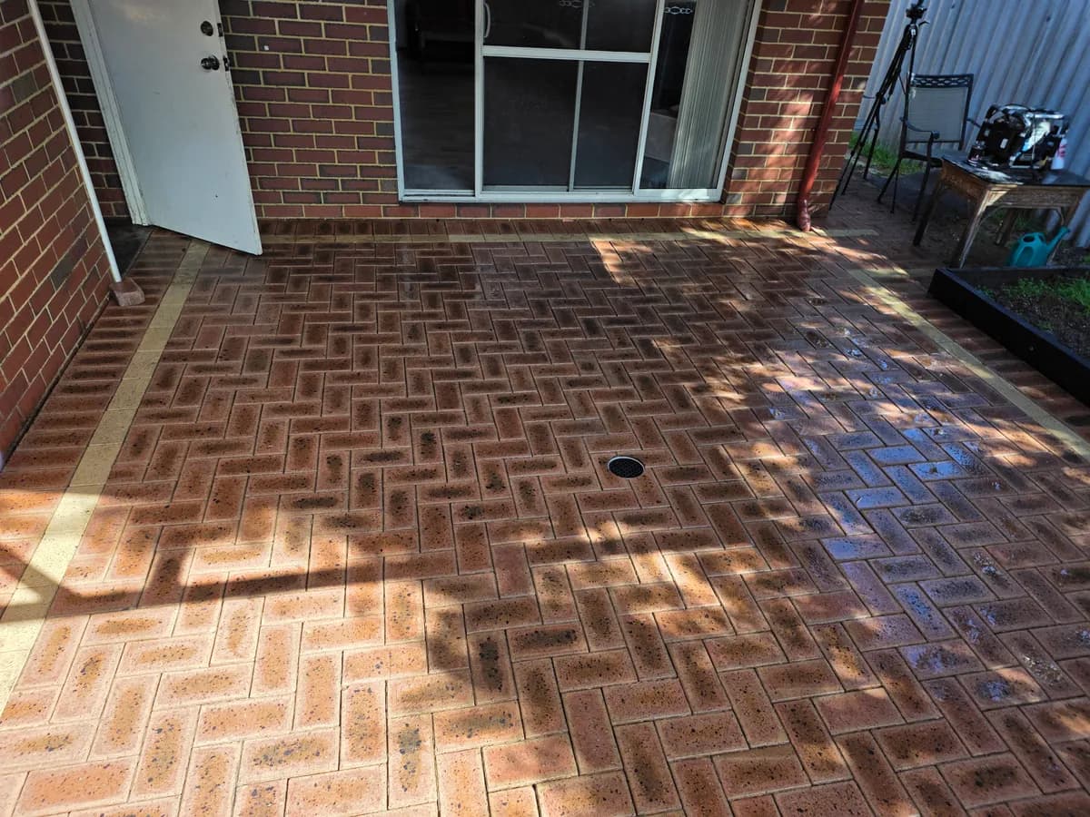 The same paved courtyard immediately after AGP pressure cleaning, with the pavers still wet.